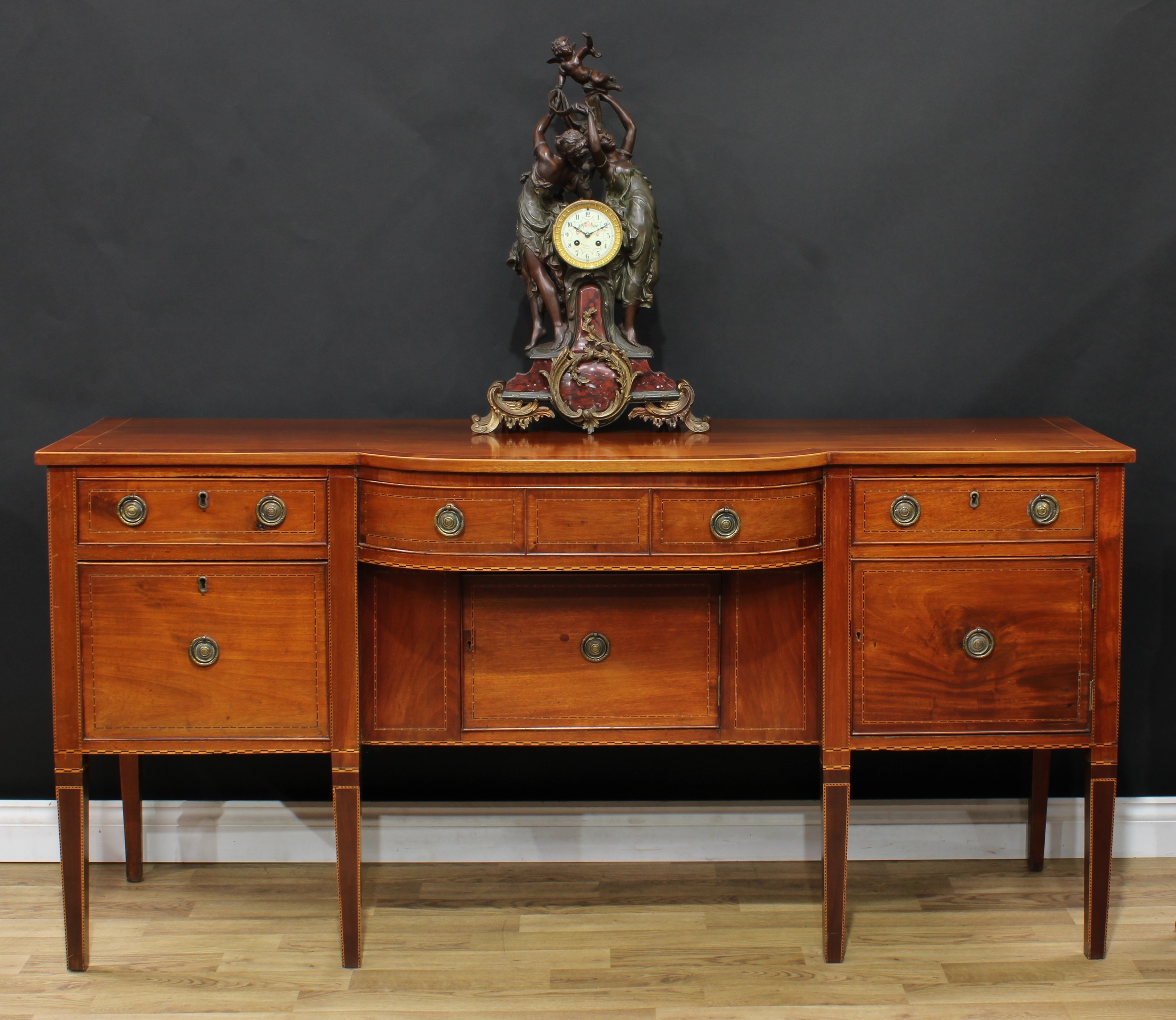 A 19th century mahogany bow-centre sideboard, crossbanded oversailing top above an arrangement of