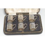 A set of six late Victorian silver spirit tots, the sleeves chased with the 18th century manner with