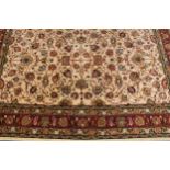A woollen carpet, worked in the traditional manner with stylised flowers and leaves, 428cm x 308cm