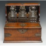 A late Victorian/Edwardian oak tantalus cabinet, three hobnail decanters, prismatic stoppers, hinged