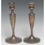 A pair of George V silver candlesticks, campana sconces, tapered pillars, spreading circular