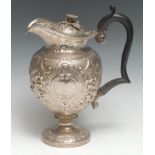 A George III Rococo silver pedestal claret jug, the ogee-shaped reservoir densely chased with