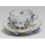 A Meissen lobed cabinet cup and saucer, painted with flowers, the exteriors encrusted, six spur