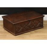 An early 18th century oak six-plank table box, hinged cover, the front carved with scrolling
