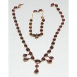 An Almandine garnet fringe necklace and bracelet suite, composed of thirty five oval graduated