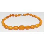 A graduated amber coloured bead necklace, twenty five multi-tone clouded beads ranging from 15mm x