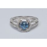 An aquamarine and diamond cluster ring, central circular aquamarine quarter claw set within an