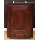 A George III oak splay-fronted wall hanging corner cupboard, moulded cornice above a rectangular