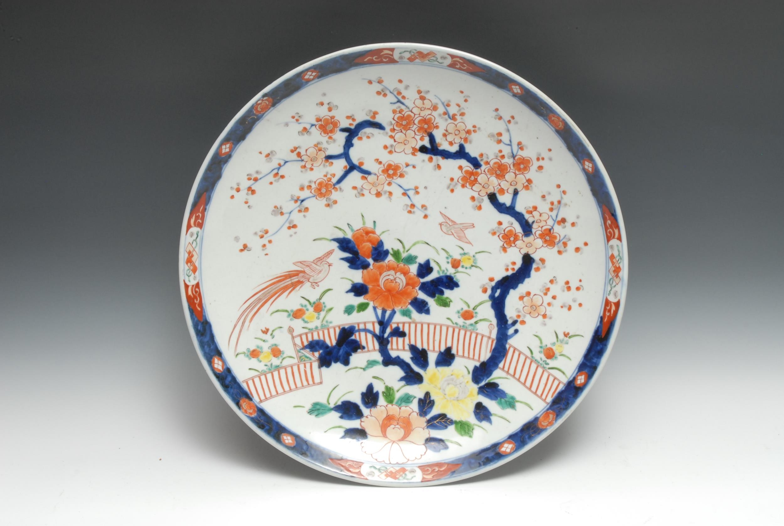 A Japanese Imari charger, decorated with stylised prunus branches, flowers, fence and stylised bird,