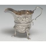 An Irish silver helmet shaped cream jug, chased in the Rococo taste with scrolling leaves and birds,