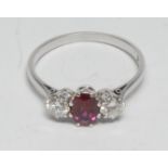 A diamond and ruby trilogy ring, central oval vibrant red ruby approx 0.85ct, between a pair of