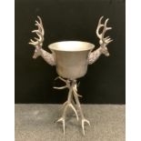 A large polished metal free standing Ice bucket with stylised stag antler handles and tripod feet,