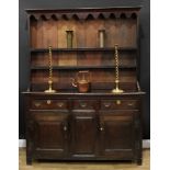 A 'George III' oak dresser, outswept cornice and shaped apron above two plate rack shelves, the