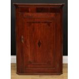 A George III oak and mahogany wall hanging splay front corner cupboard, moulded cornice above a