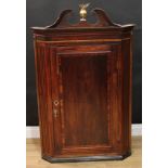 A George III mahogany corner cabinet, swan neck pediment centred by a brass globular finial