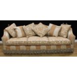 A Knole type drop arm sofa, of country house proportions, hinged arms crested with spiral finals,