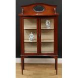 An Edwardian mahogany display cabinet, serpentine arched cresting with bevelled oval mirror, bow