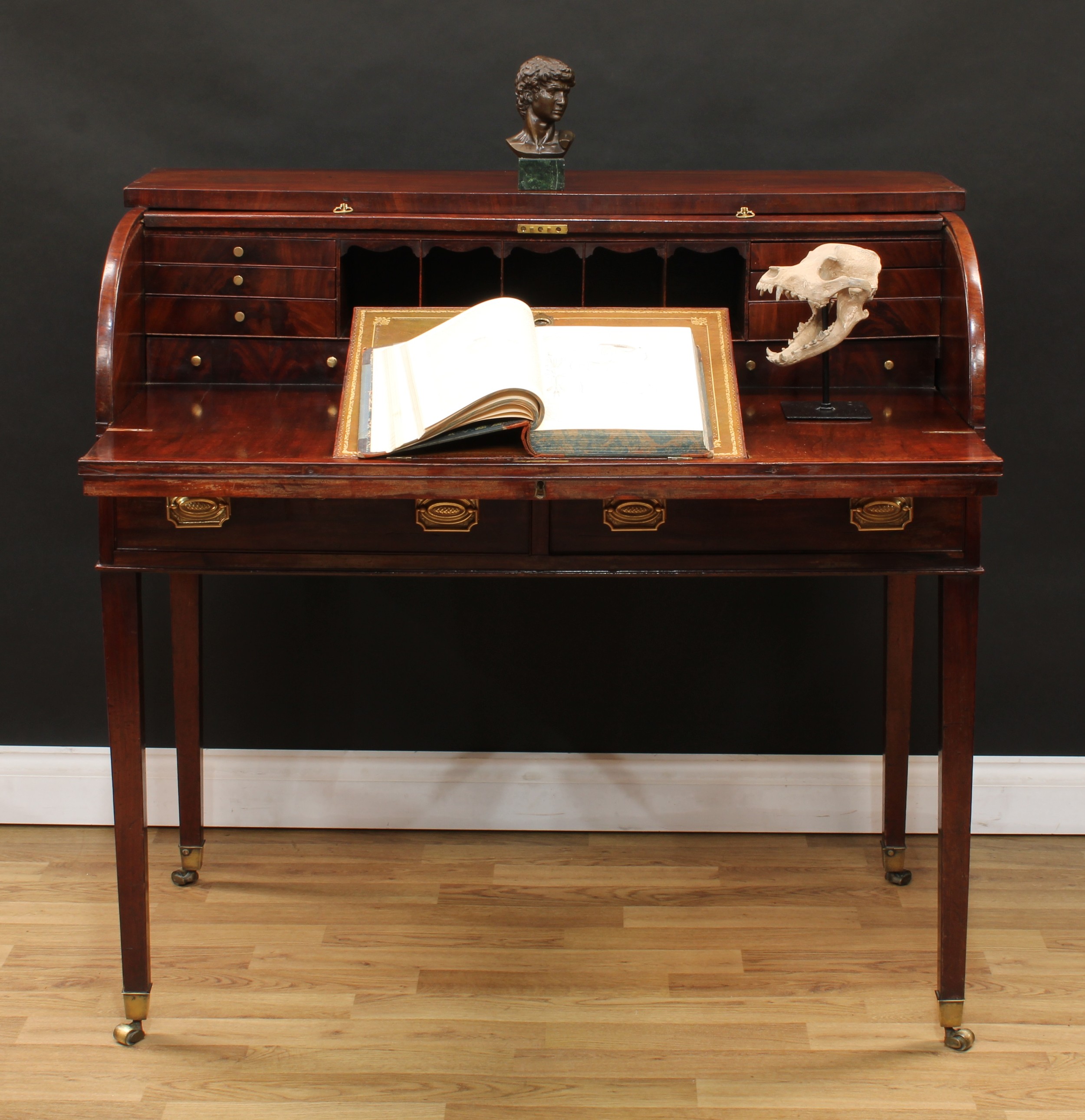A George III mahogany tambour-fronted writing desk, oversailing top above a retractable front