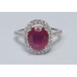 A ruby and diamond cluster ring, larger oval mid red ruby measuring approx 10.37mm x 8.76mm x 5.65mm