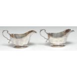 A pair of George V silver panelled sauceboats, double scroll handles, 16cm long, Mappin and Webb,