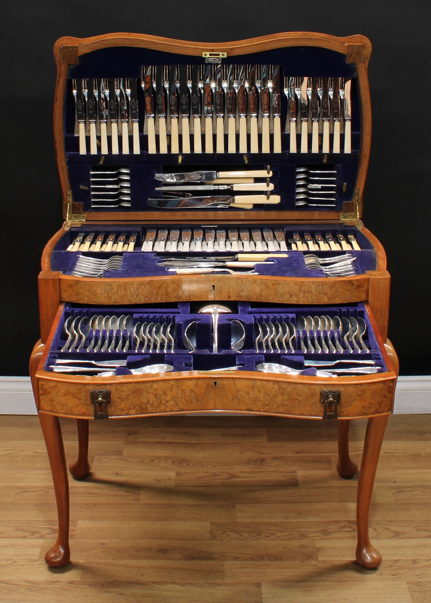 An Art Deco period burr walnut serpentine canteen table, enclosing a George VI service of silver