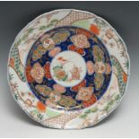 A Japanese shaped circular charger, the centre painted in the Imari palette with precious objects