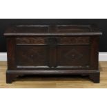 An 18th century oak blanket chest, hinged top above a floral lunette frieze and a two panel front,