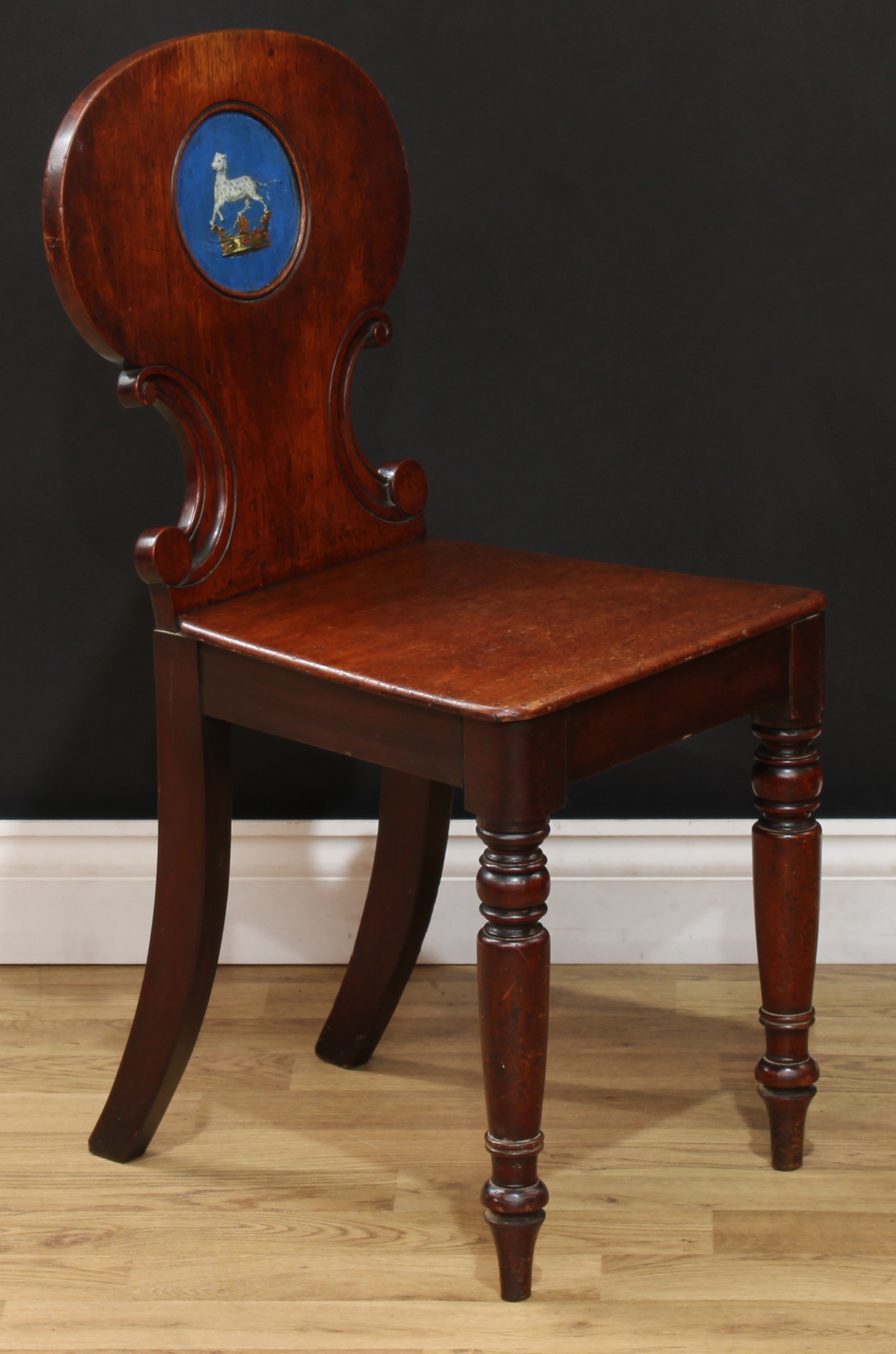 A Victorian mahogany heraldic hall chair, shaped back carved with C-scrolls and polychrome painted