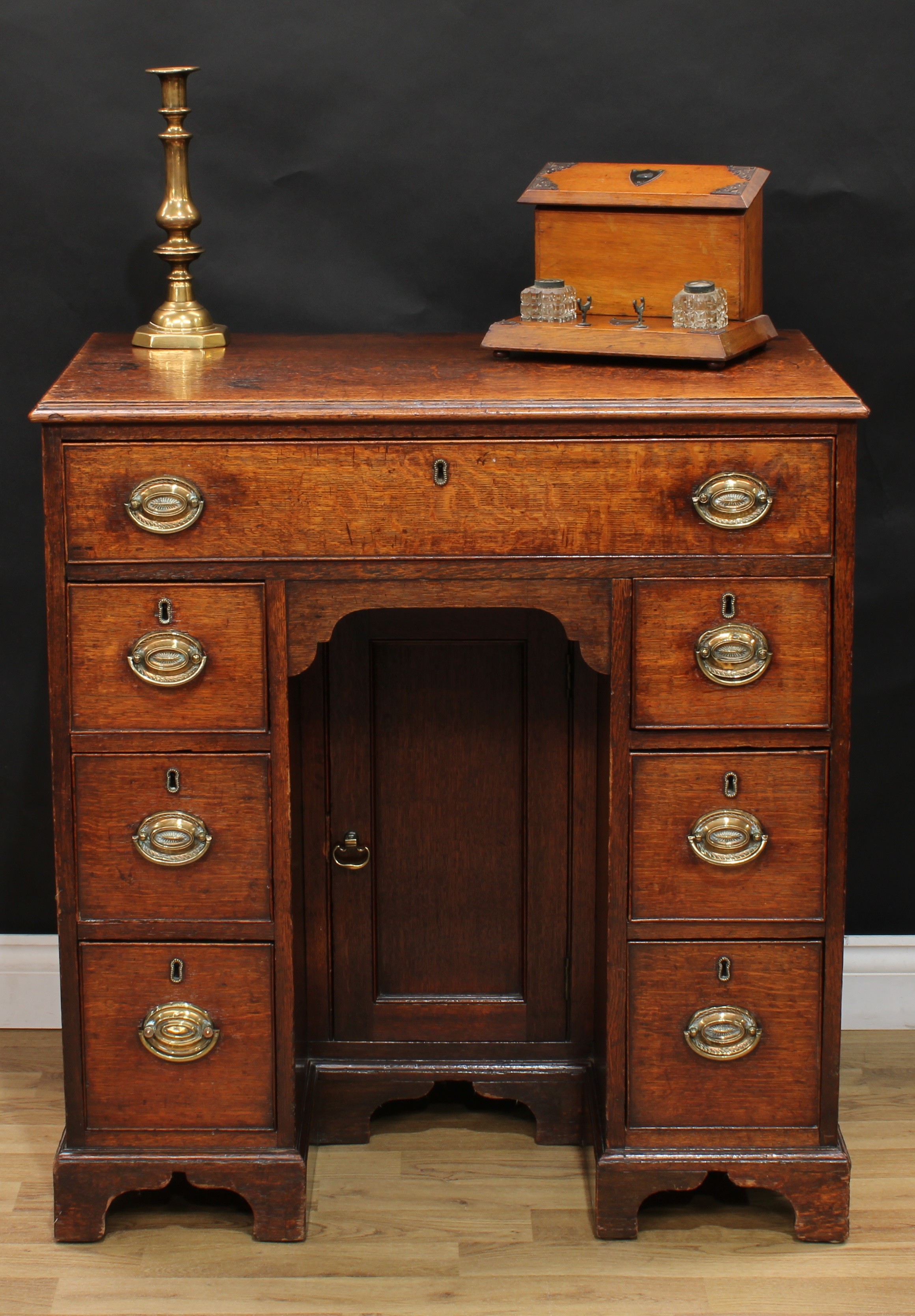 A George III oak kneehole desk, rectangular top with moulded edge above a long cockbeaded frieze
