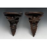 A pair of Black Forest wall brackets, carved as eagles, perched and facing to left and right,