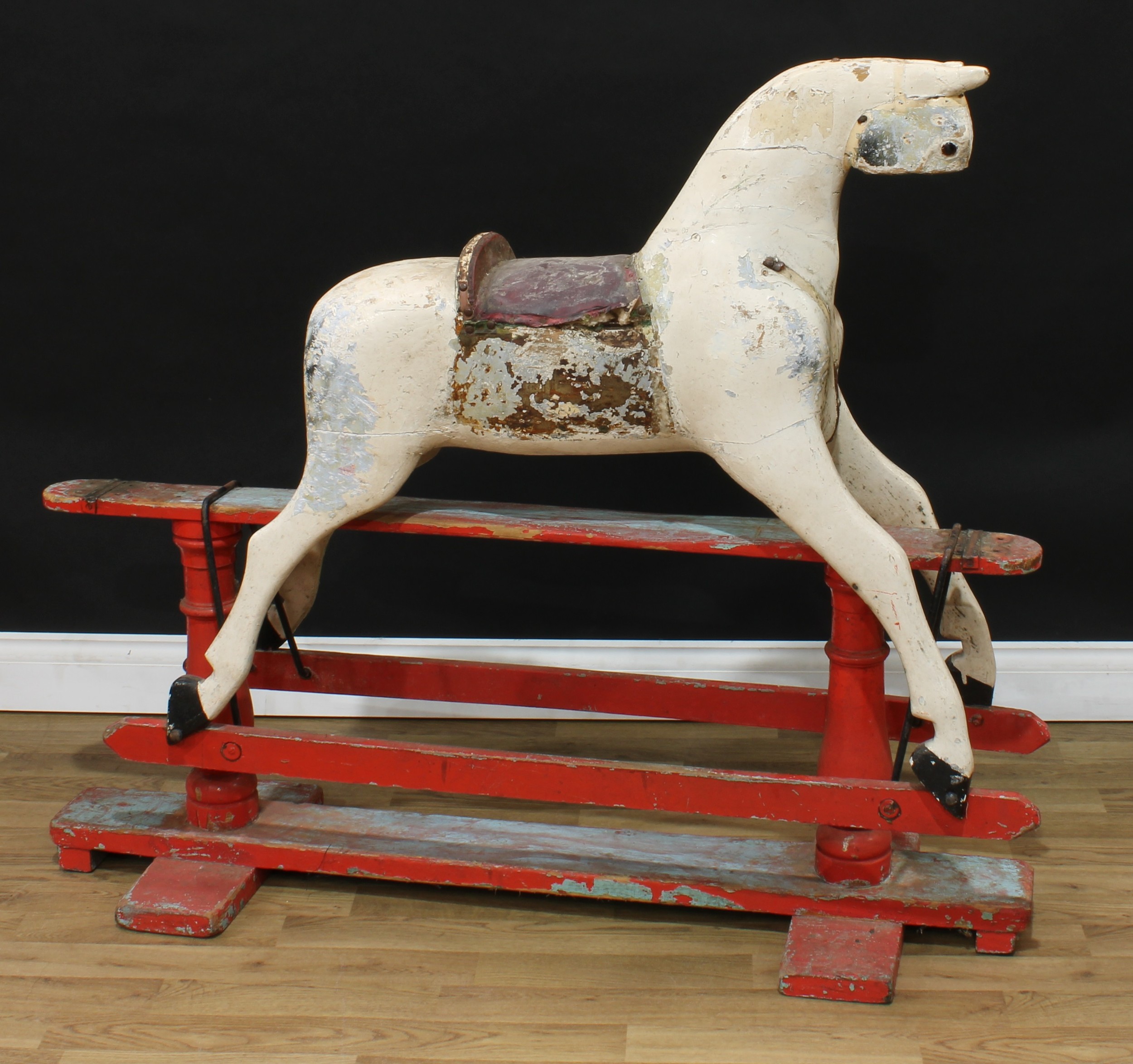 A late 19th/early 20th century English rocking horse on safety stand, the partially stripped and