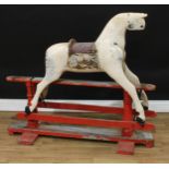 A late 19th/early 20th century English rocking horse on safety stand, the partially stripped and