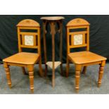 A pair of Victorian carved oak hall chairs, each back inset with a John Moyr Smith for Minton