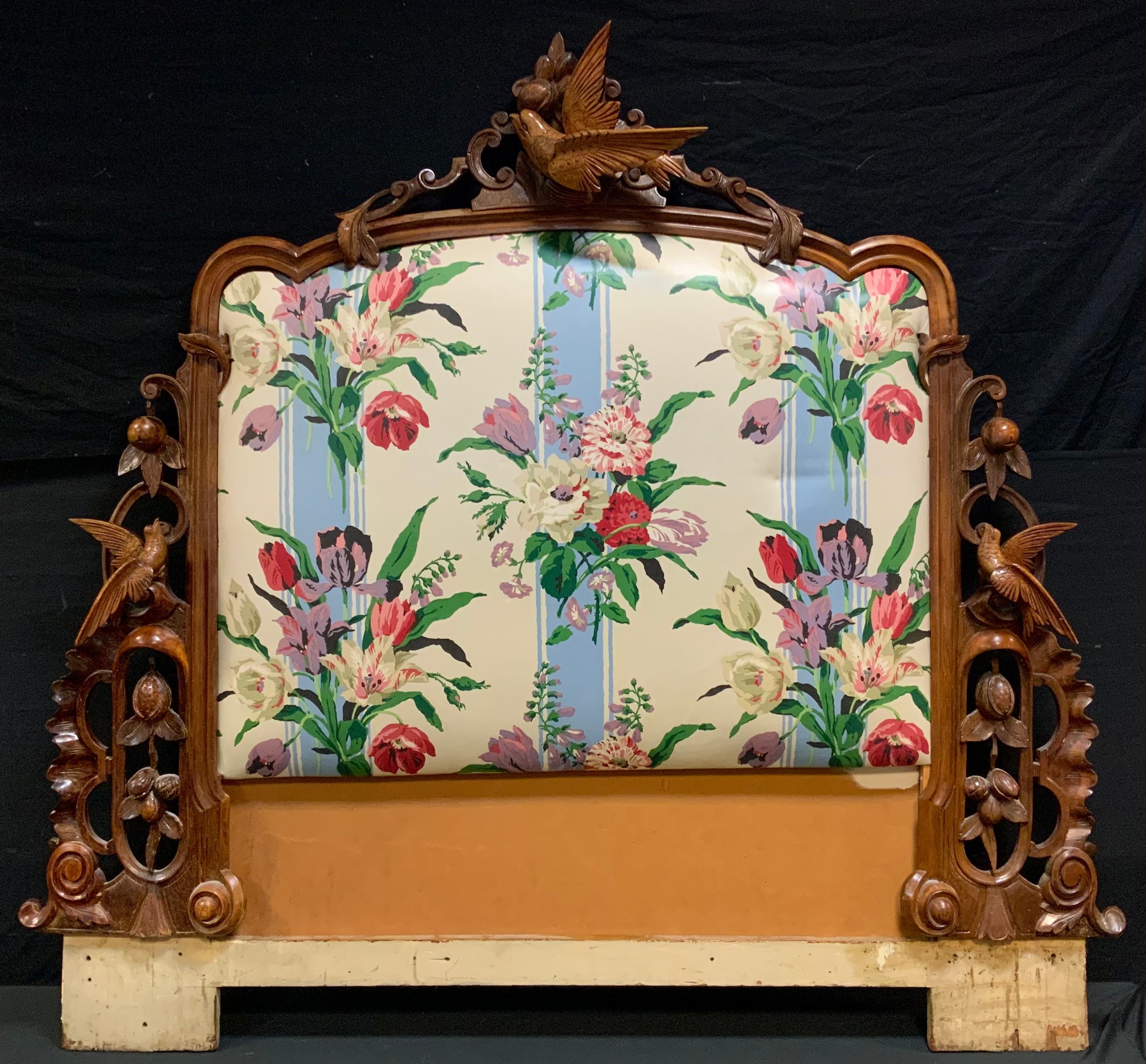 An early 20th century walnut and upholstered bed head, carved with birds and fruit, approx. 138cm
