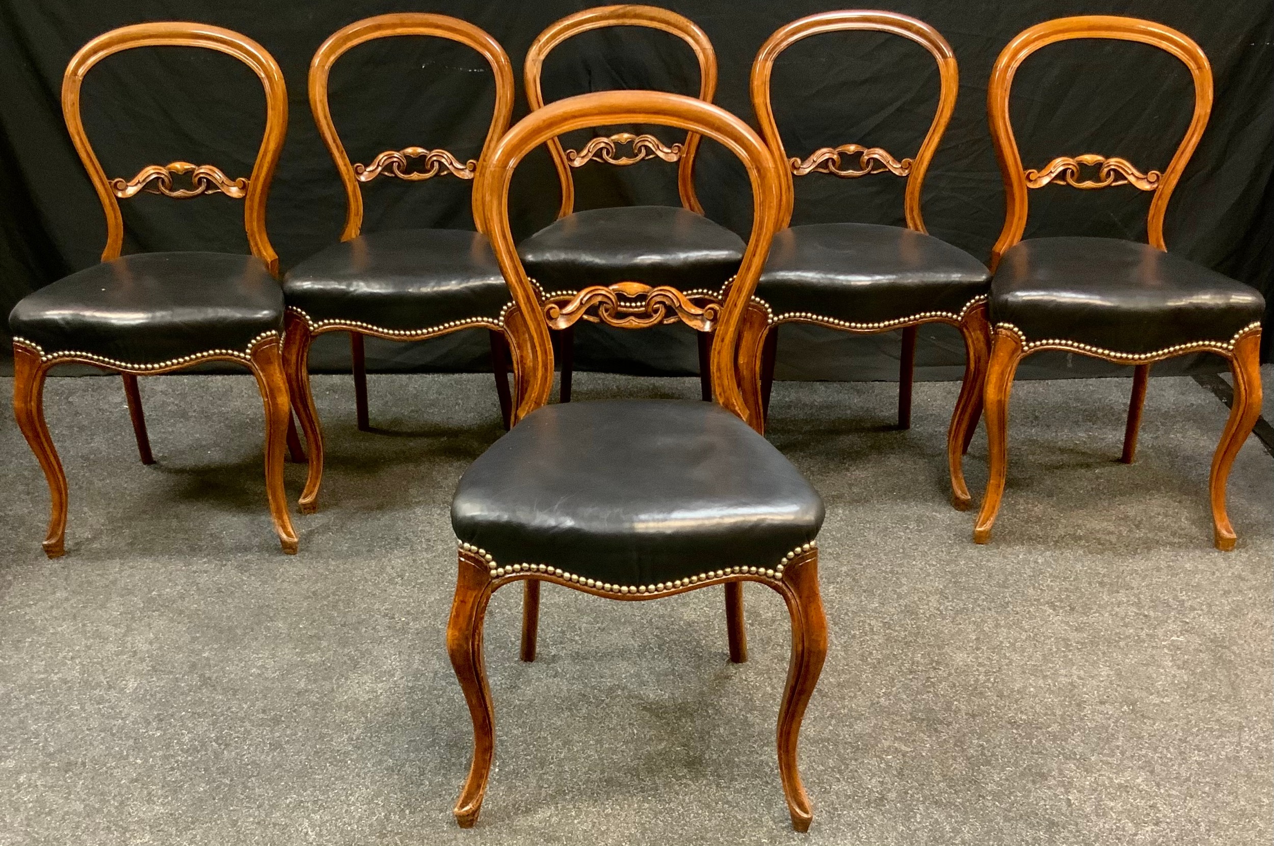 A set of six Victorian mahogany kidney back dining chairs, stuffed over brass studded leatherette