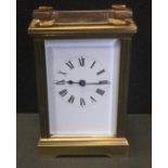 An early 20th century brass carriage clock, white dial, black Roman numerals, bevelled glass panels,