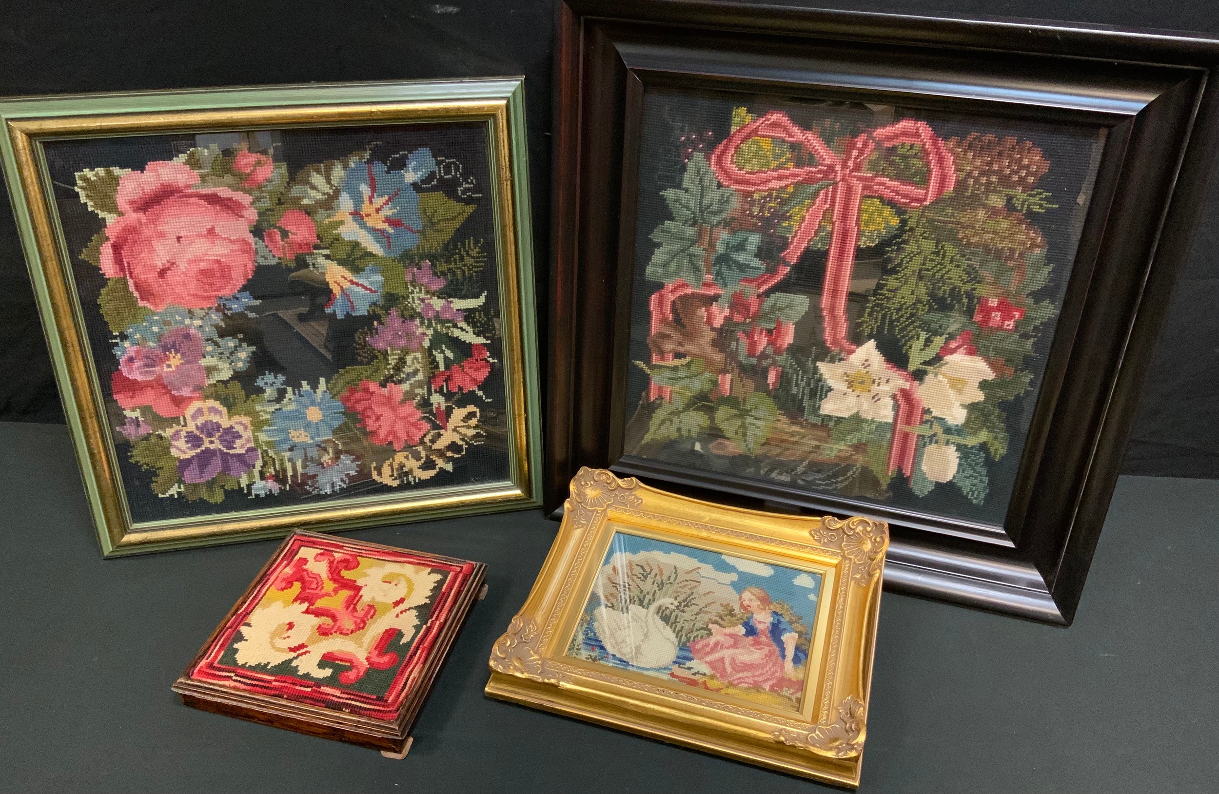 A Victorian woolwork, embroidered with ribbon tied wreath, 40cm square, framed; another, smaller,