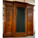 A large Victorian mahogany breakfront wardrobe, with arched mirrored door, flanked by two arched