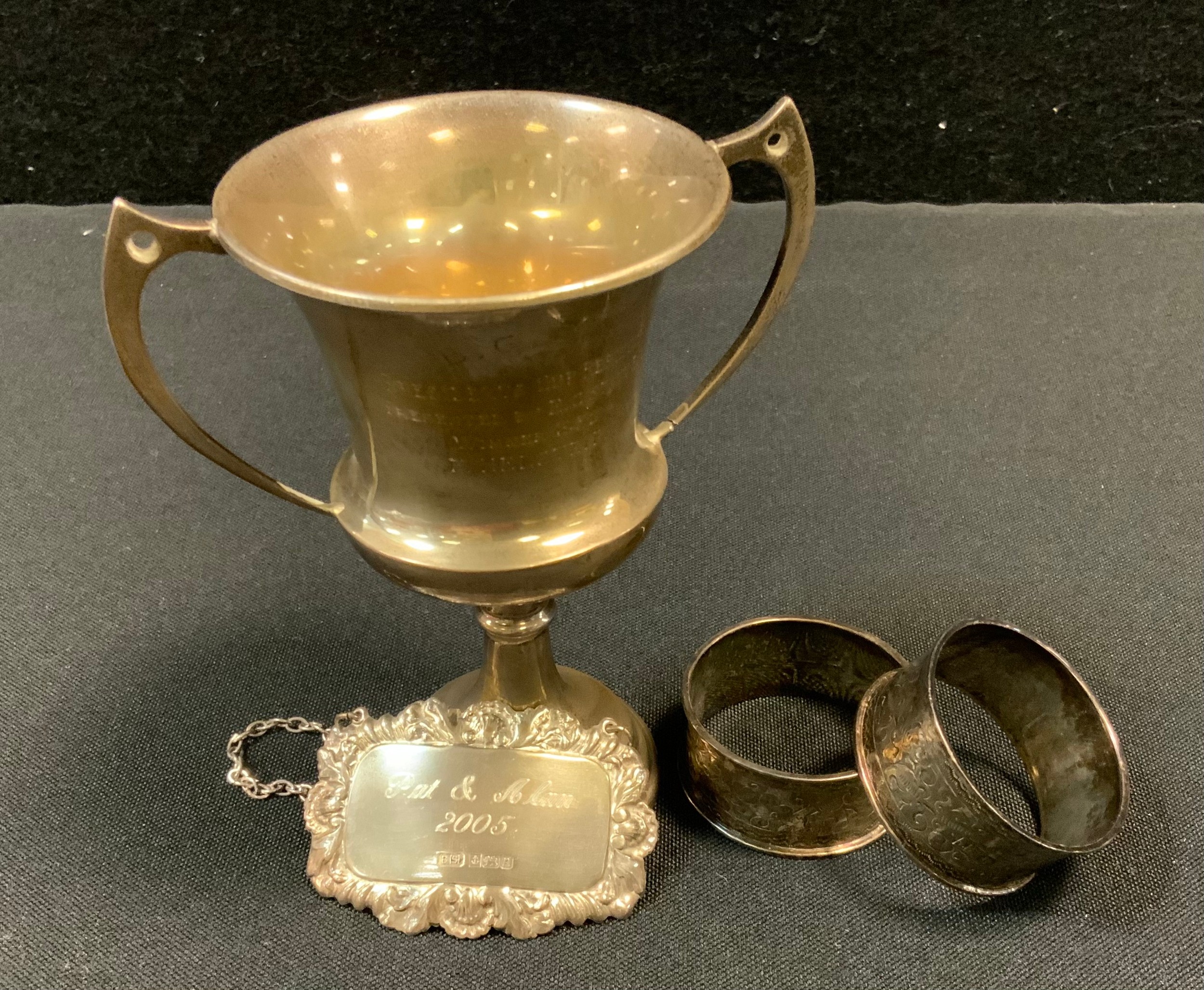 A George V silver twin handled trophy cup, Sheffield 1931; a pair of silver napkin rings; a decanter