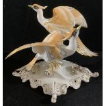 A Royal Crown Derby model of Twin Chelsea Birds, standing on a branch with wings partly stretched,