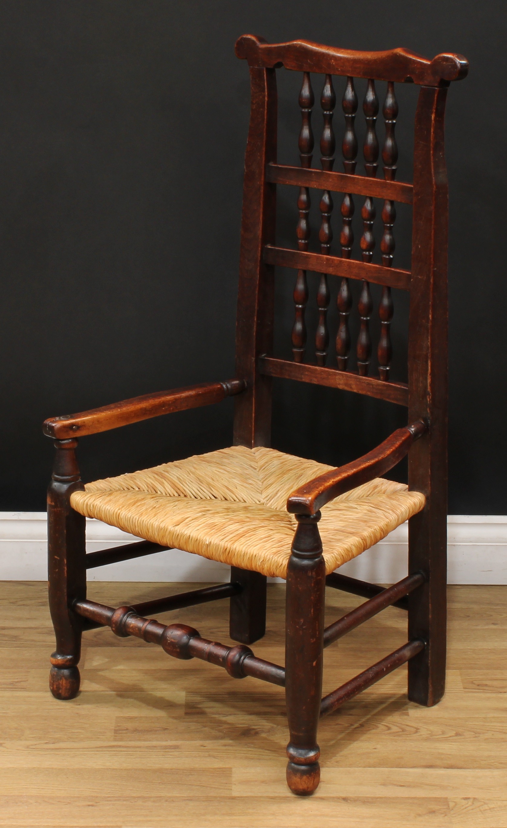 A 19th century rush seated spindle-back elbow chair, turned front stretcher, 96cm high, 52cm wide,