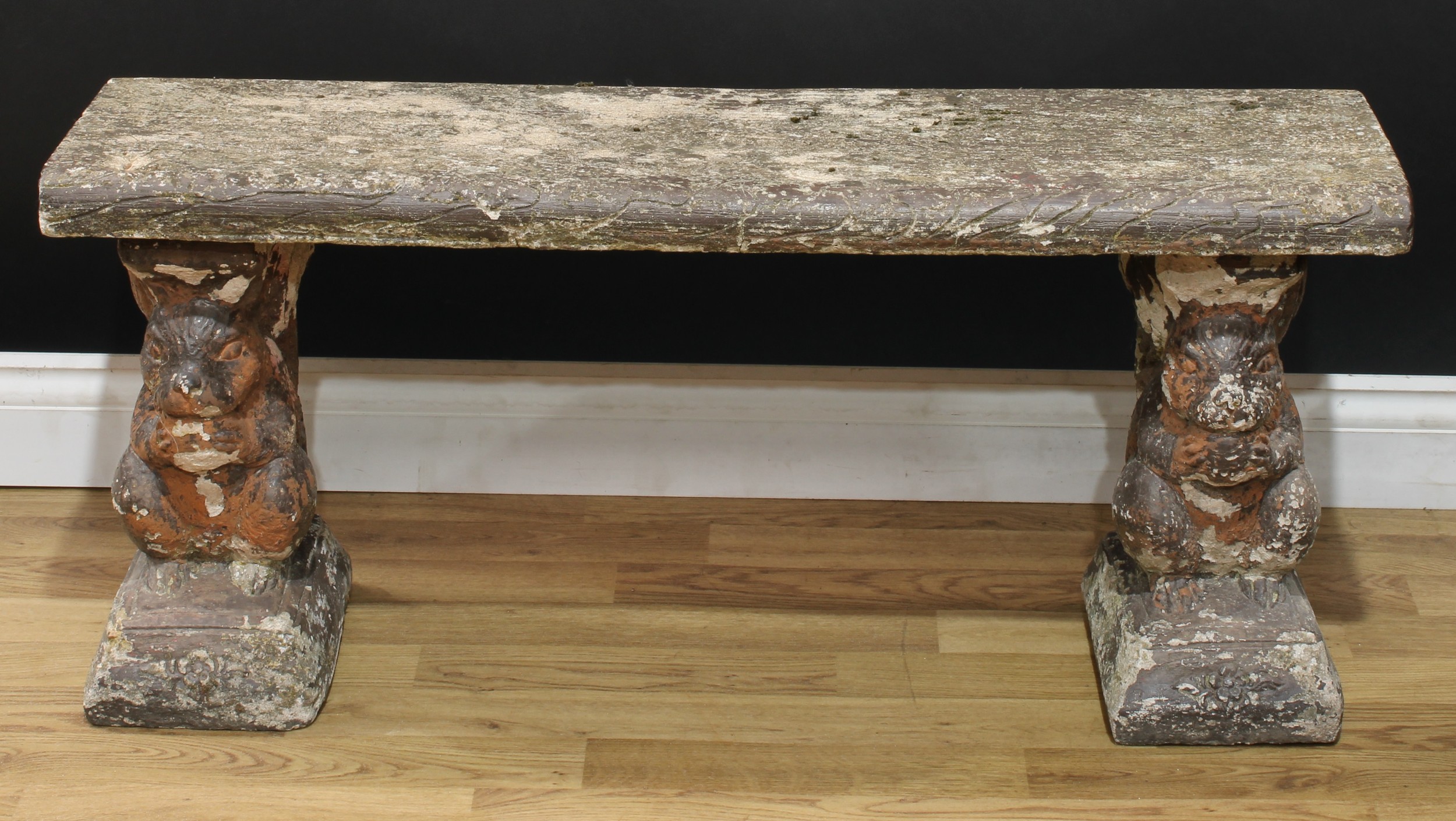 A reconstituted stone garden bench, the end supports cast as squirrels, 44cm high, 101cm wide,