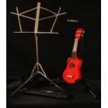 A Puretone ukulele in red, soft carry case; an XCG Frontline adjustable guitar stand; a Percussion