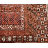 A Middle Eastern woollen rug, the centre with tow rectangular fields decorated with blue, ochre