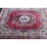 A Chinese woollen carpet, with central floral cartouche, the ground with scrolls on a pink ground,