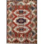 An Indian kazak woollen rug, the field with three geometrical panels, in blue, brown and cream, on a