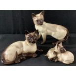 A Beswick model of a Siamese cat, standing; another, recumbent; a model of two kittens (3)
