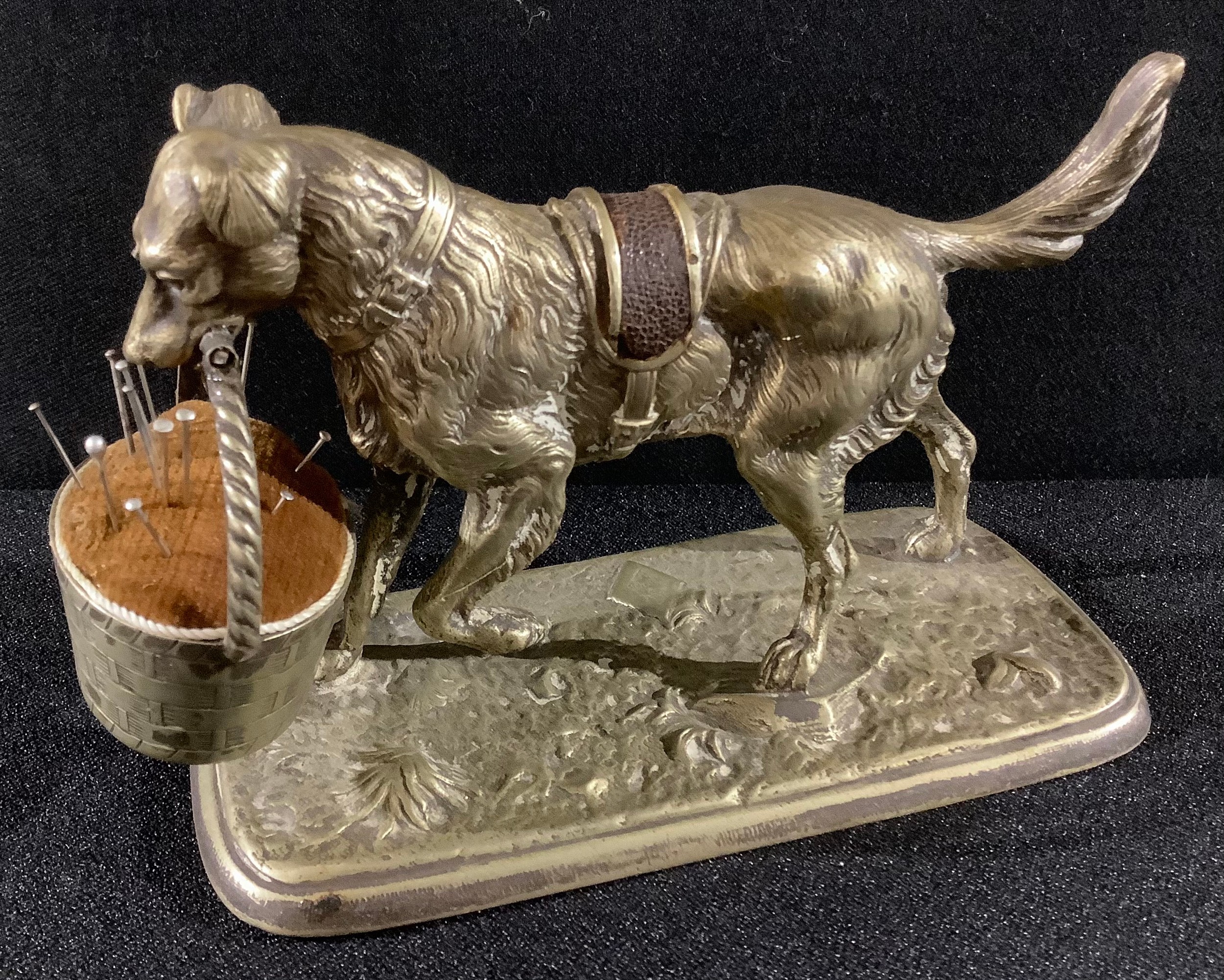 A Victorian cast metal pin cushion modelled as a dog with basket, kite mark to maquette, 15cm long