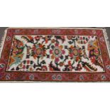 A woollen rug, the rectangular field with stylised flowers and foliage, red banded border with