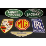 A reproduction cast iron sign, Porsche; others, Land Rover, Aston Martin, Jaguar, Rolls Royce, MG